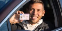 Conducente di un'auto esibisce la sua patente di guida